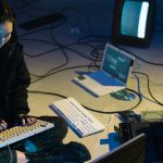 Pessoa utilizando laptop com escudo digital simbolizando segurança online